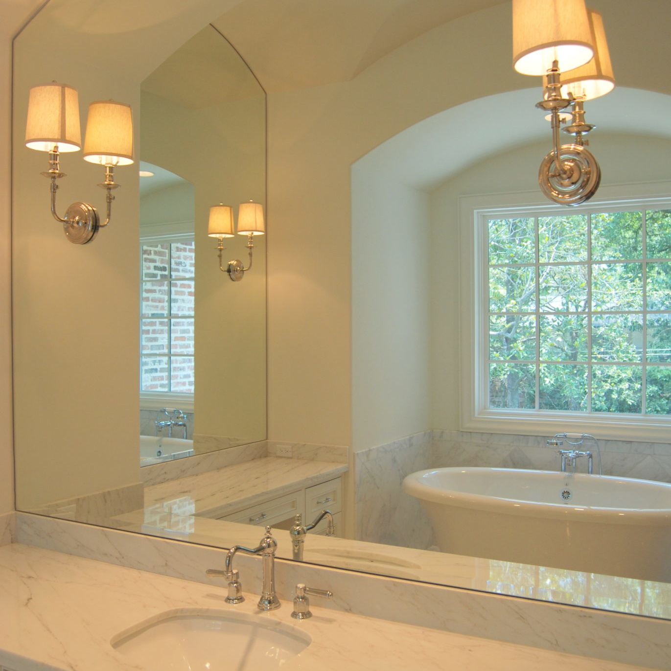 Newly remodeled bathroom with white marble countertops and large mirror