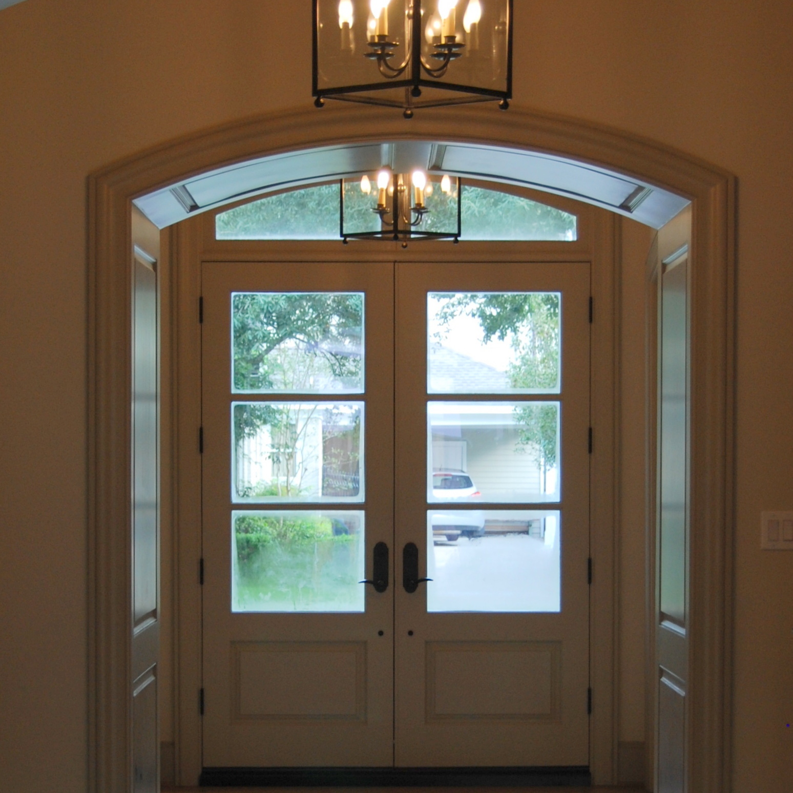 Entryway with large doors and modern chandeliers