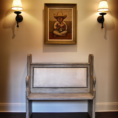 Wooden bench with a portrait above it and two wall lights
