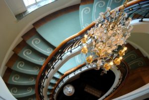 Luxury stairway design with crystal chandelier and blue carpet